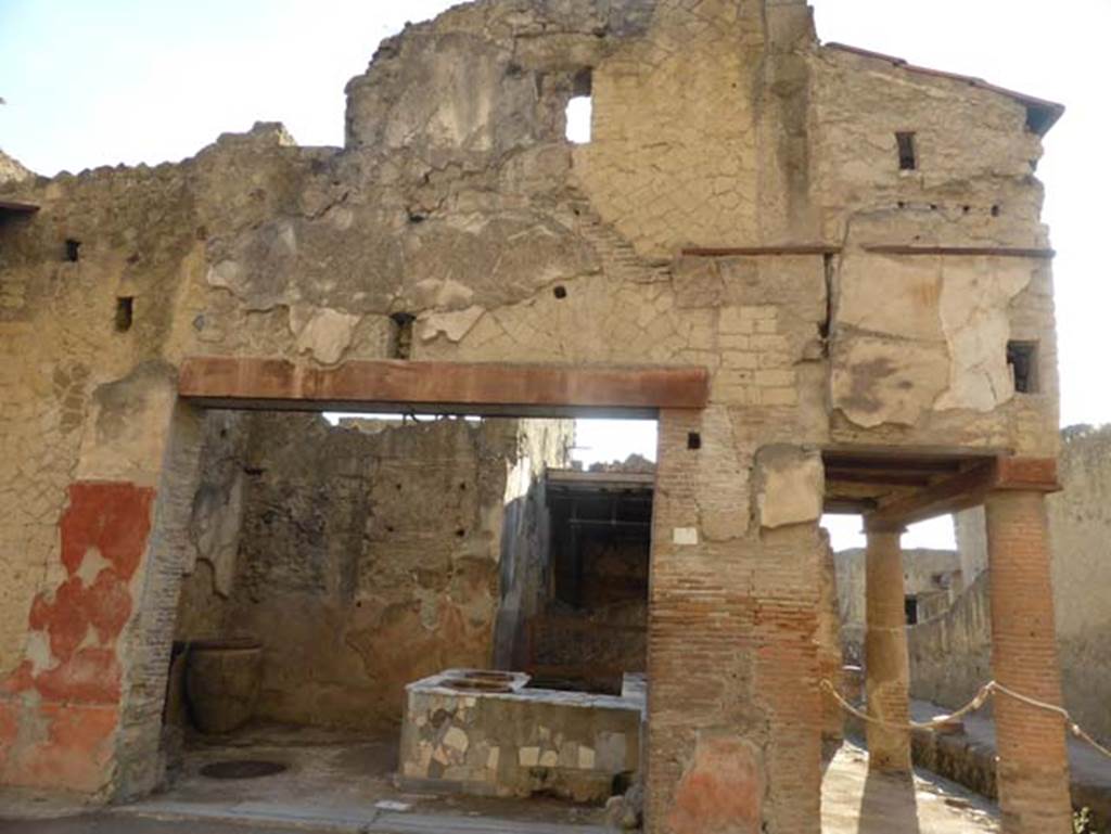 V.10, Herculaneum, September 2015. Looking south to entrance, on the right is Cardo IV Superiore. According to Maiuri, in this shop the big pots set into the ground can be seen, which preserved cereals and dried vegetables. For the same purpose the little porch of the pavement on the western side was used, a lot of cereals were actually found here). The shop belonged to the following dwelling (at V.11), as is clearly shown by the little door, through which the two dwellings were connected.
See Maiuri, Amedeo, (1977). Herculaneum. 7th English ed, of Guide books to the Museums Galleries and Monuments of Italy, No.53 (p.45).